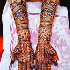 A beautiful example of full-arm bridal mehndi with heavy, intricate work. The design uses a mix of traditional jaal patterns and bold floral motifs to create a rich and dense look, perfect for a royal wedding theme.