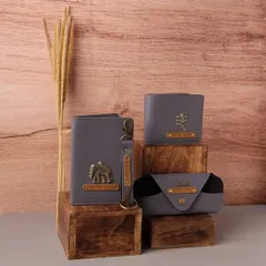 This coordinated gift set for men is crafted from stylish grey vegan leather. It includes a personalized passport cover with an elephant charm, a matching wallet with a rupee symbol charm, a keychain, and a spectacle case.
