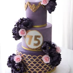 Celebrating 75 glorious years with a cake that’s fit for royalty. This three-tiered masterpiece features a regal purple ganache finish, intricate gold stenciling, and a cascade of handmade sugar peonies and roses. The top two tiers were a delicate pistachio rose, with a rich chocolate cake for the base.