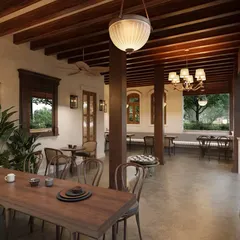 The ground-floor patio offers a covered dining experience that still feels connected to the outdoors. Exposed wooden beams and pillars were preserved and reinforced, maintaining the home's original architectural language.