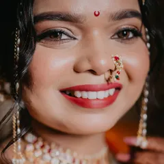 A close-up showcasing the flawless airbrush makeup on our Maharashtrian bride. The classic red lip and intricate nath complete this timeless look.