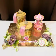 A truly luxurious baby girl hamper featuring ornate golden jars with pink tassels and a musical carousel centerpiece.