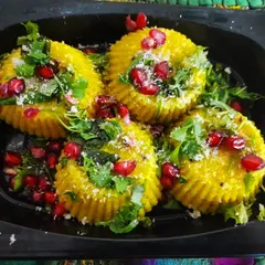 A fun and modern take on a classic: Nylon Khaman presented as bite-sized savory cupcakes. They are garnished with fresh coriander, coconut, and pomegranate jewels.