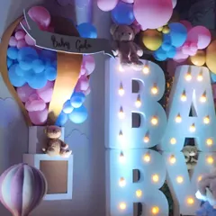 This whimsical baby shower featured large marquee letters, teddy bears nestled in pastel balloon clouds, and a custom hot air balloon prop, creating a dreamy and joyful atmosphere.