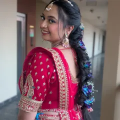 A breathtaking bridal braid for a destination wedding. This long, thick braid is woven with vibrant blue and white flowers, creating a unique and unforgettable statement hairstyle.