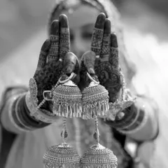 A creative black and white shot focusing on the bride's kalire, held up in her mehndi-covered hands.
