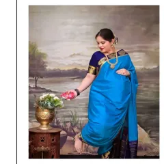 Inspired by the grace of figures in Raja Varma's paintings, this pose captures the mother-to-be in a traditional blue saree. The painted landscape backdrop and antique brass vase add to the artistic, heritage feel of this unique maternity portrait.