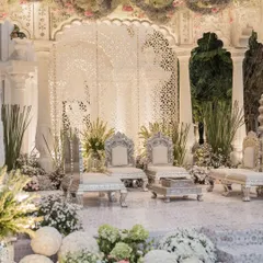 For this wedding, I designed a mandap that exudes ethereal elegance. It features intricate white jaali screens, ornate silver chairs for the couple, and a ceiling adorned with a thick layer of moss and hanging florals.