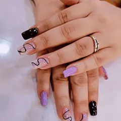 For the client who wants a bit of everything, I created this mismatched set. It combines solid black and lavender nails with clear extensions featuring freehand black swirl line art for a creative and personalized manicure.