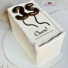 A toast to 35. This sleek, rectangular cake features edible, balloon-shaped numbers and a simple "Cheers! Happy Birthday My Love" message, perfect for a modern and stylish celebration.