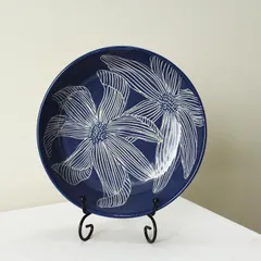My Dutch Iris pasta bowl displayed as a piece of decorative art. The intricate, hand-carved floral pattern stands out against the deep indigo blue, making it a statement piece.