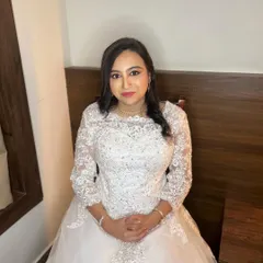 A seated portrait of the bride in her gorgeous white gown. This angle shows the delicate lace sleeves and the soft, romantic feel of the entire look.