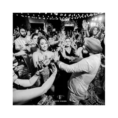 The couple surrounded by their loved ones on the dance floor, a candid moment of shared joy and celebration.