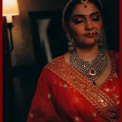 A moody and cinematic bridal portrait. The play of light and shadow adds drama and highlights the intricate details of her jewelry and the rich color of her lehenga.