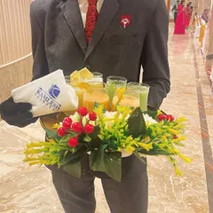 A member of our hospitality team serving welcome drinks. The tray is beautifully decorated with flowers, and our branded napkins add a professional touch, ensuring your guests feel welcomed from the very first moment.