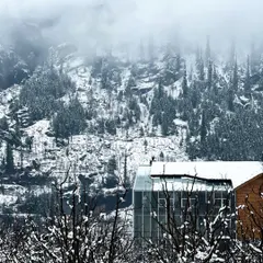 The modern form of the Hamsa Resort's spa building emerges from the misty, forested slopes of Manali. The design juxtaposes a contemporary steel and glass structure with buildings that utilize traditional Kathkuni timber and stone construction.