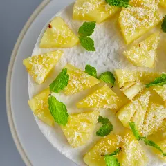 A top-down view of my Coconut Pineapple cake. The fresh pineapple chunks, mint leaves, and sprinkle of coconut create a tropical escape on a plate.
