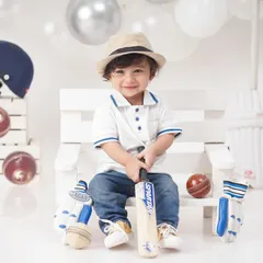 A future cricket star in the making, this little boy is all smiles in a 'Little Cricketer' themed shoot, complete with a bat, balls, and helmet.