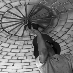 The final touches. A craftsman carefully works on the central point of a brick dome, a testament to the patience and handcrafted excellence that defines our building process.