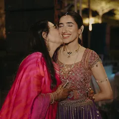 A mother's love. A tender kiss for her daughter, the mother's vibrant pink saree a beautiful pop of color next to the bride's intricate ensemble.