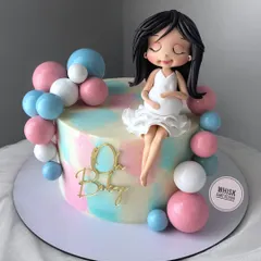 Your dream baby shower cake is here. This elegant cake features a beautiful, handcrafted figurine of a mom-to-be, surrounded by pink and blue balloons.