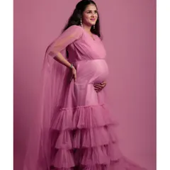 This full-length shot shows the beautiful layers and flow of the pink maternity gown against a solid pink backdrop for a soft, cohesive look.