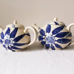 A pair of 'Bloom & Brew' teapots, each with slight variations in the hand-painted floral design. They make a beautiful set for serving tea or as decorative objects.
