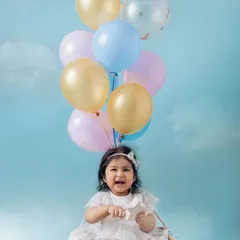 Up, up, and away for her first birthday. This 'hot air balloon' setup with pastel balloons against a dreamy blue sky creates a whimsical and happy portrait. I love designing creative themes for baby milestone photoshoots.