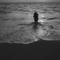 A minimalist and moody black and white shot of a couple embracing in the water. The simplicity of the composition focuses all the attention on their connection against the vastness of the sea and sky.