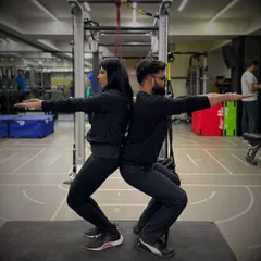 Partner workouts help with form and motivation. Here, a couple works on posture and squat depth together, providing support and accountability.