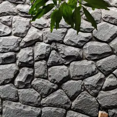 A close-up of the random rubble stone wall at the Siri residence. The texture of the natural stone, combined with the foliage, creates a rich, organic surface.