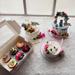 A beautiful collection of orders ready to go out. It includes two floral cakes, a car-themed cake, and a box of assorted cupcakes.