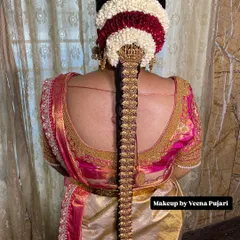 An exceptionally grand bridal hairstyle. This features a traditional braid fully covered in intricate gold jewelry (jada), topped with a bun of fresh jasmine and rose petals.