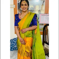 A classic combination of a vibrant yellow and green silk saree paired with a custom royal blue raw silk blouse. The blouse features elegant puff sleeves and delicate embroidery on the cuffs.