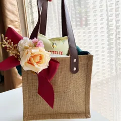 A chic jute tote bag designed as a room hamper for wedding guests. The sturdy leather handles and elegant floral bow make it a stylish and practical gift that guests can use throughout their stay and beyond.