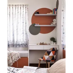 A closer look at the study corner in the kids' room. A simple white desk is set against a creative backdrop of circular painted shapes and floating shelves, creating an inspiring spot for homework and hobbies.