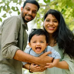 A close-up, joyful portrait of a family enjoying their time together outdoors. The baby's wide-open laugh is infectious and shows the real, happy moments I strive to capture.