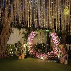 For a modern and romantic engagement, I crafted this stunning circular floral arch. The abundance of pink blossoms, combined with hanging glass orbs and a ceiling of twinkling lights, makes for a perfect photo backdrop and a truly memorable moment.
