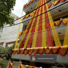 A traditional home exterior decoration using classic red and yellow drapes. This is a popular choice for creating a festive and auspicious look for any home-based wedding function.