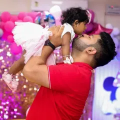 A father's love captured in a candid moment, lifting his daughter high during her first birthday party.