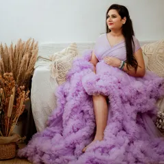 We always aim for a variety of poses during a session. This candid shot captures a natural, relaxed moment, showing off the incredible texture and flow of the ruffled gown while the mom-to-be enjoys the serene studio environment.