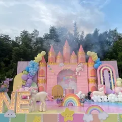 A fairytale unicorn-themed first birthday, complete with a magnificent pink castle backdrop. The setup includes pastel balloon arrangements, fluffy clouds, and adorable unicorn figures, creating a dreamy setting for a magical milestone.