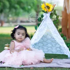 A portrait of a little princess in her pink dress, sitting in front of our sunflower-themed tent. This setup is perfect for a whimsical first birthday photoshoot.