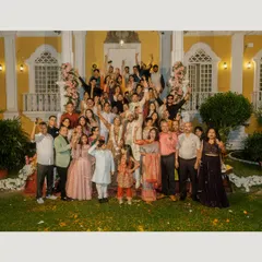 A fun and energetic group photo with all the wedding guests celebrating with the couple in front of their beautiful Goa venue.
