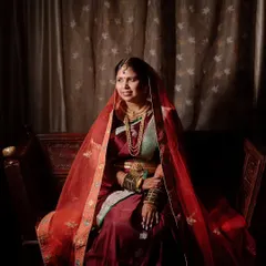 A classic and regal portrait of a Maharashtrian bride. The dramatic lighting and rich colors of her saree create a timeless, painting-like quality.