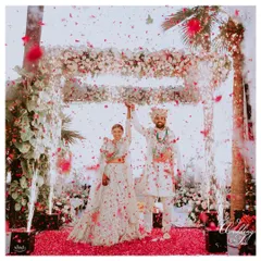 A perfect Varmala moment captured under a canopy of flowers, with cold pyrotechnics adding to the magic of their union.