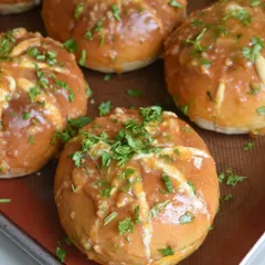 A close-up of our Korean Cream Cheese Bun, golden brown and topped with fresh parsley. They are available for walk-ins and on Zomato.