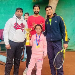 Three of our coaches celebrating with a young U8 champion in her pink tracksuit. This picture captures the supportive team environment we build around our players at our Vikaspuri center.