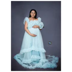 A full-length shot of an expecting mother holding a bouquet of blue hydrangeas, perfectly complementing her gown and hinting at the joy to come.