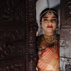 A striking bridal portrait, with the bride peeking through a beautifully carved wooden door. The play of light and shadow adds a touch of mystery and artistry to the image.